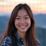 Portrait of Sophia Chen, an energetic female guide with camera gear, smiling warmly.